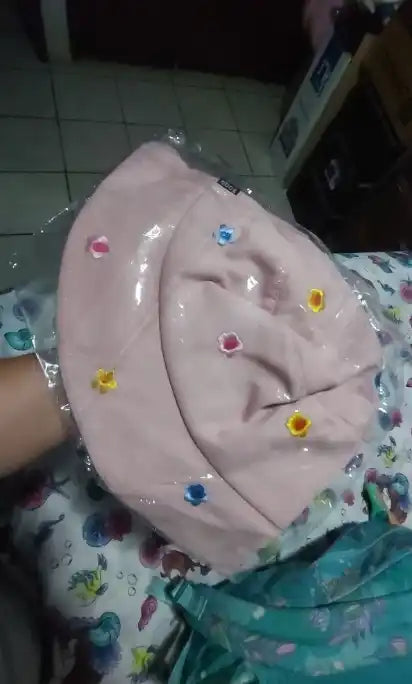 Chapeau seau rose avec des accents floraux.