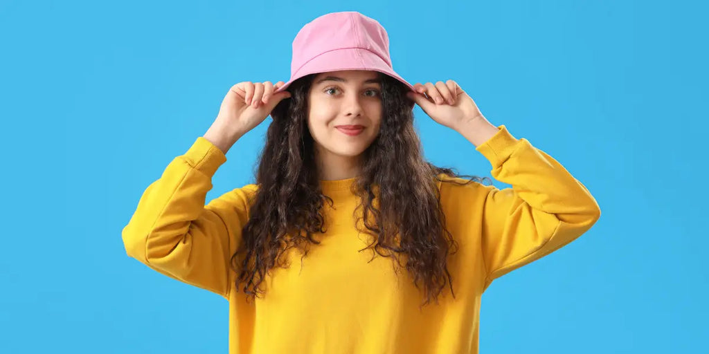 Femme portant un pull jaune et un bob rose